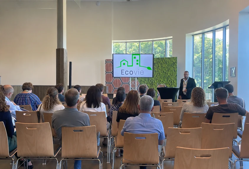 Conférence EcoVie dans une salle moderne avec le logo à l'écran